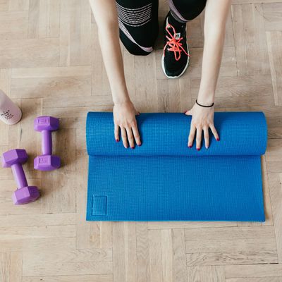 A neatly rolled up yoga mat on a wooden floor.